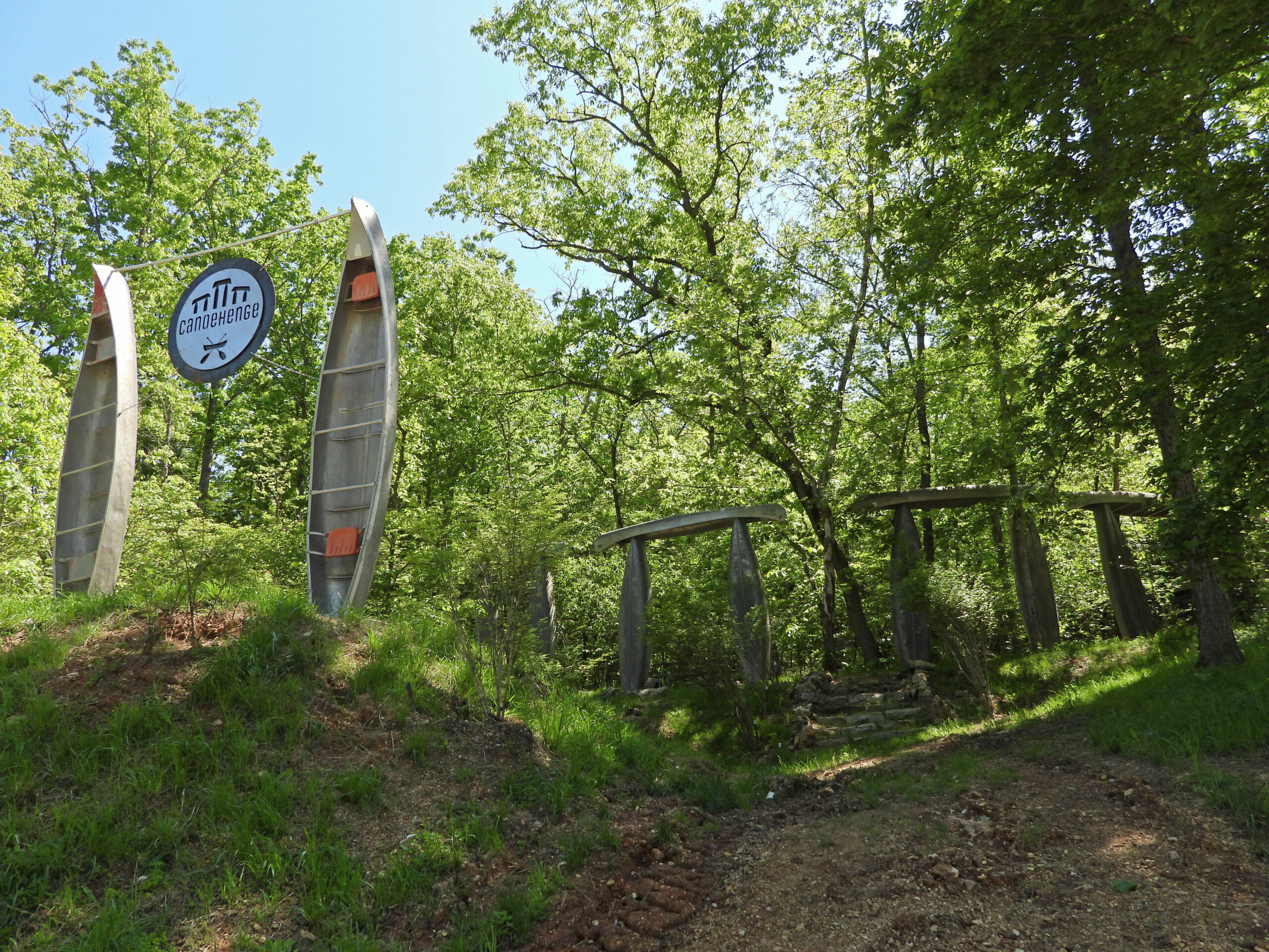 Two canoes standing upright as trail markers on a wooded hillside at Ozark Outdoors