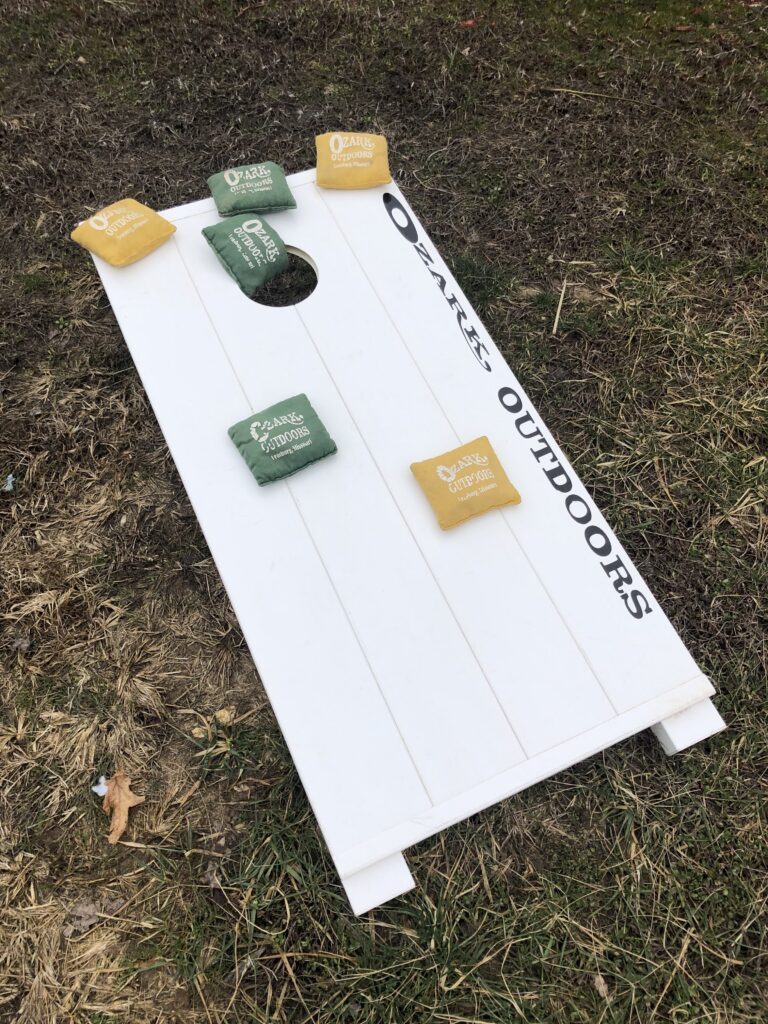 Ozark Outdoors branded cornhole board with bean bags on the grass
