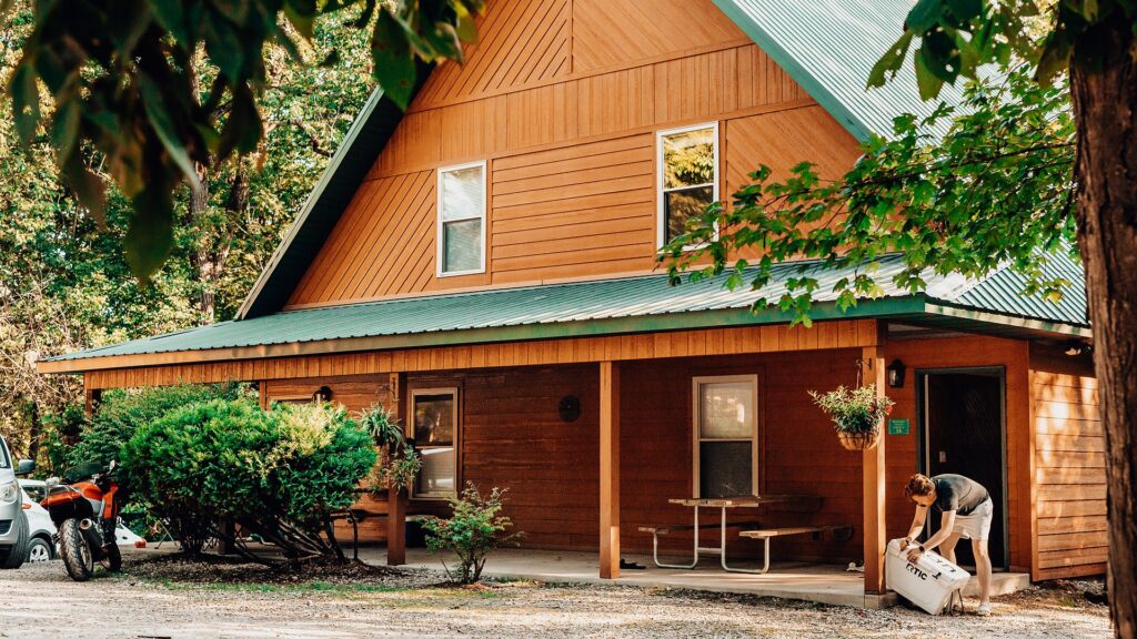 A-frame cedar lodge with a green metal roof and a covered front porch with picnic table