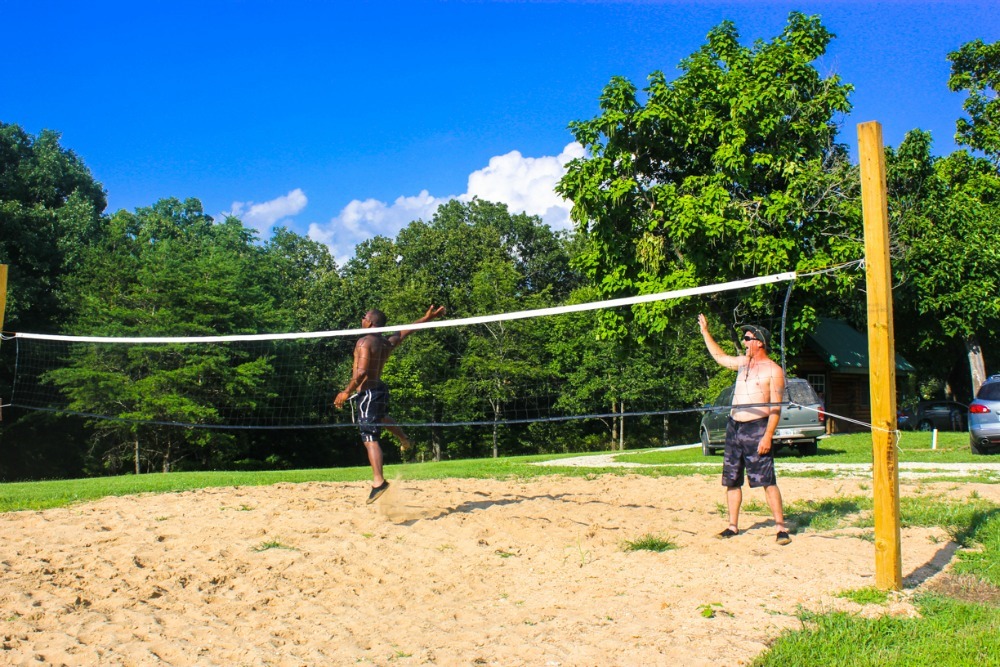 Two guests playing sand volleyball on the court at Ozark Outdoors Resort